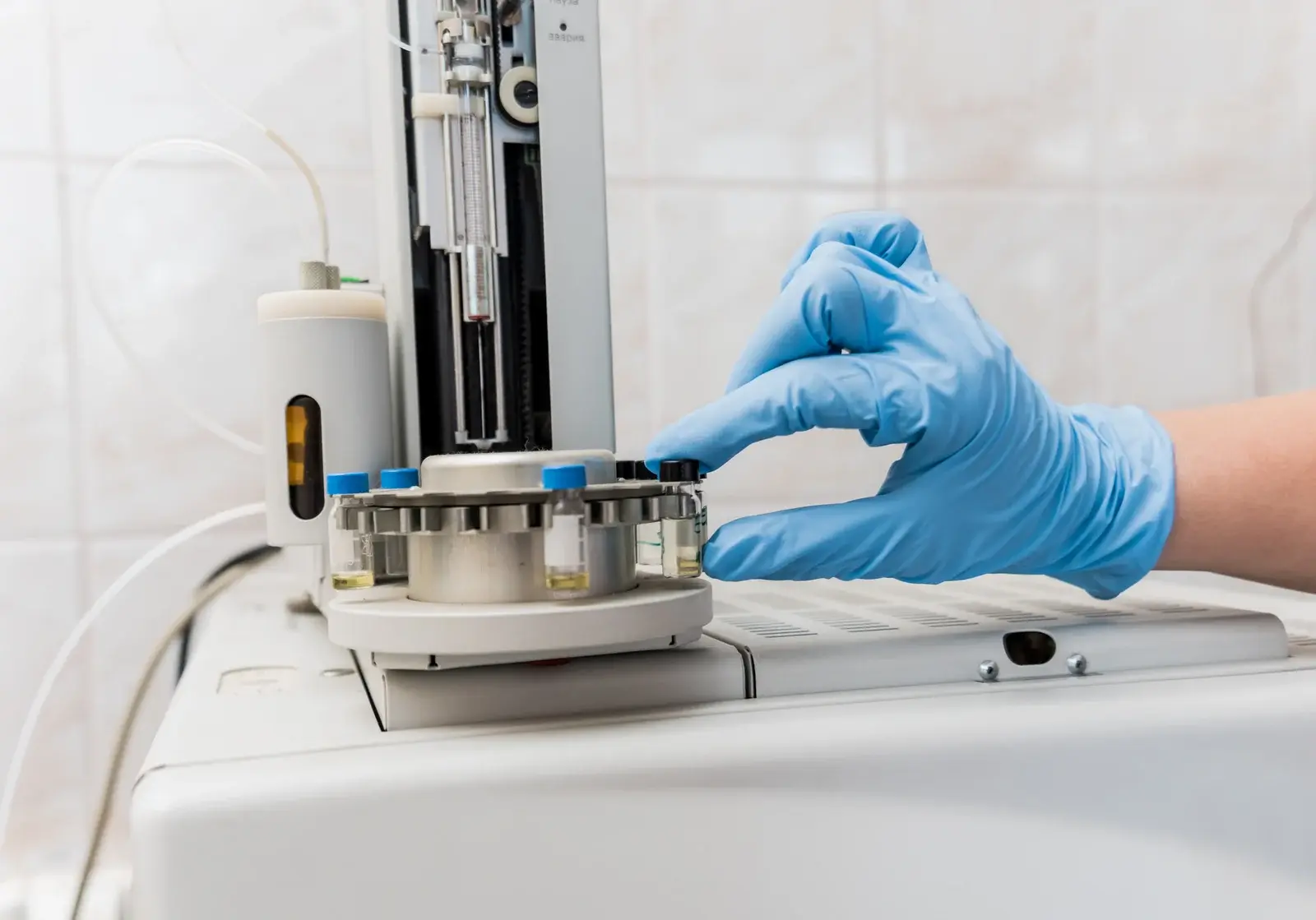 Gloved laboratory professional placing a sample vial into an analytical instrument