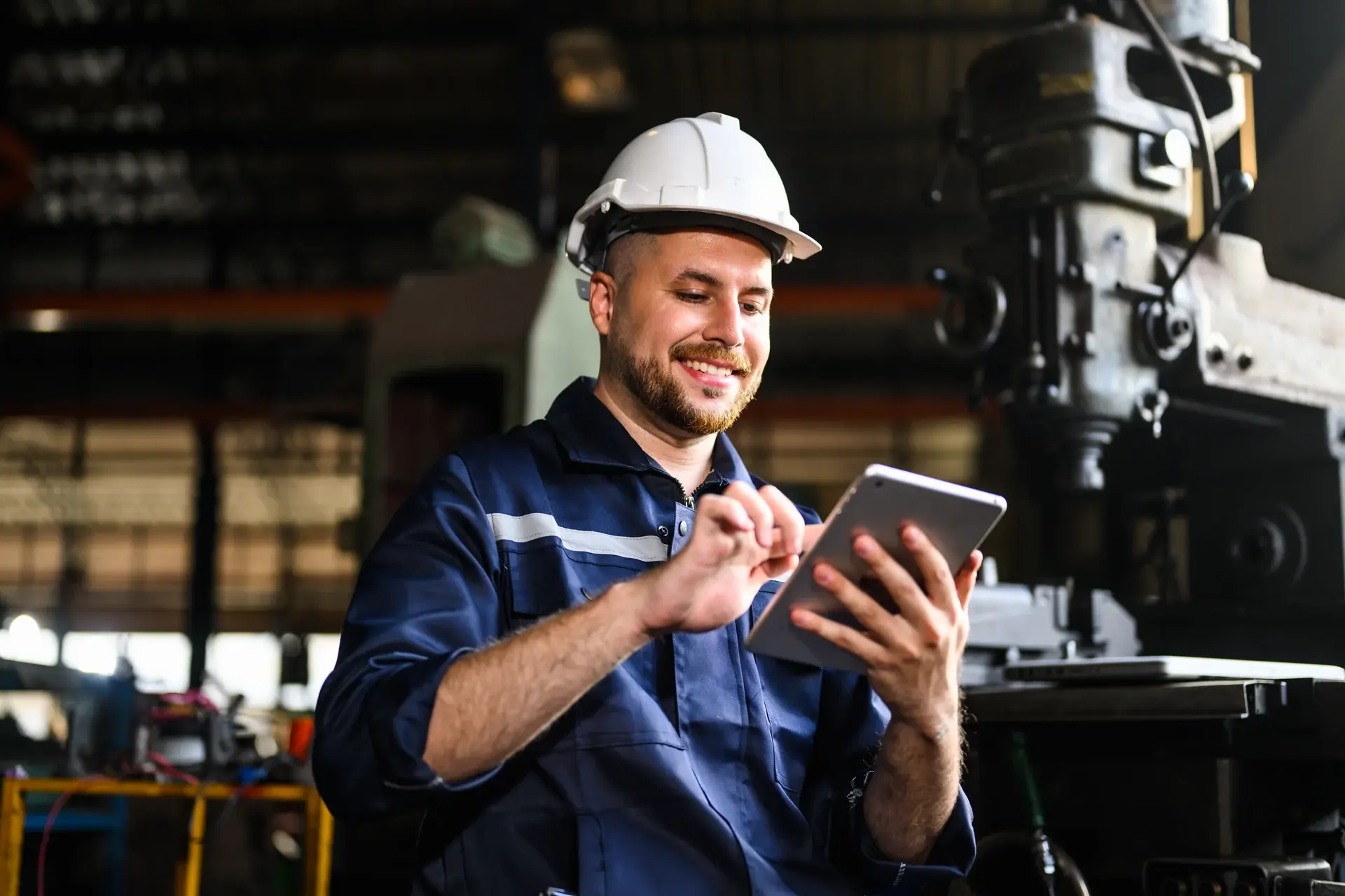 Service technician checking a tablet beside industrial equipment